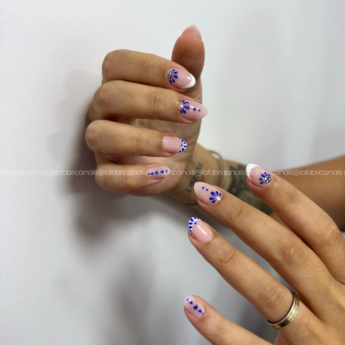 Diseño de uñas con pequeños motivos azules sobre base rosa